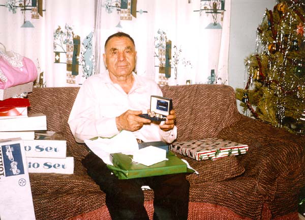 Jacob Mahler showing off a gift with a Christmas tree next to the couch