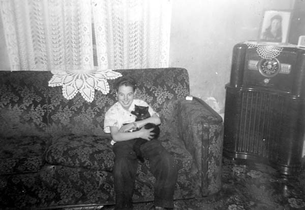 Michael as a boy, sitting on a couch and holding a cat